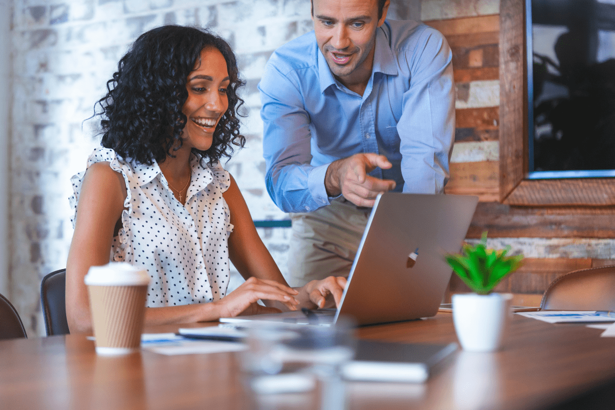 Woman and man looking and pointing at computer smiling